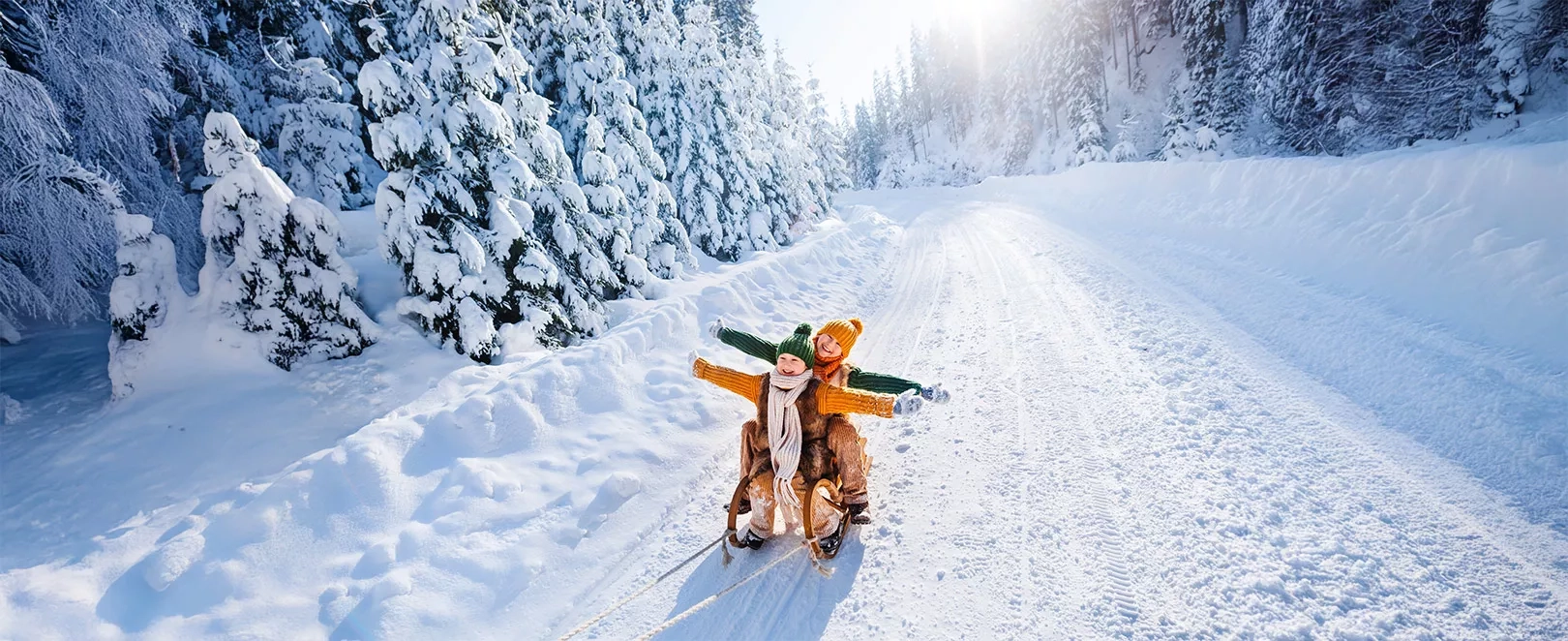 2 enfants qui écartent les bras sur une luge dans un paysage enneigé de Laponie