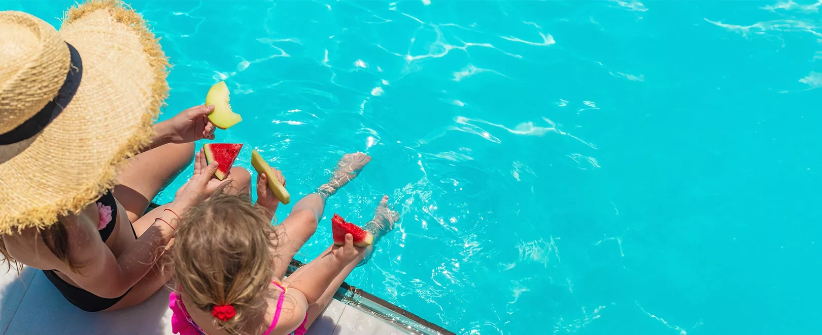 Mère et fille les pieds dans l'eau mangeant une tranche de pastèque