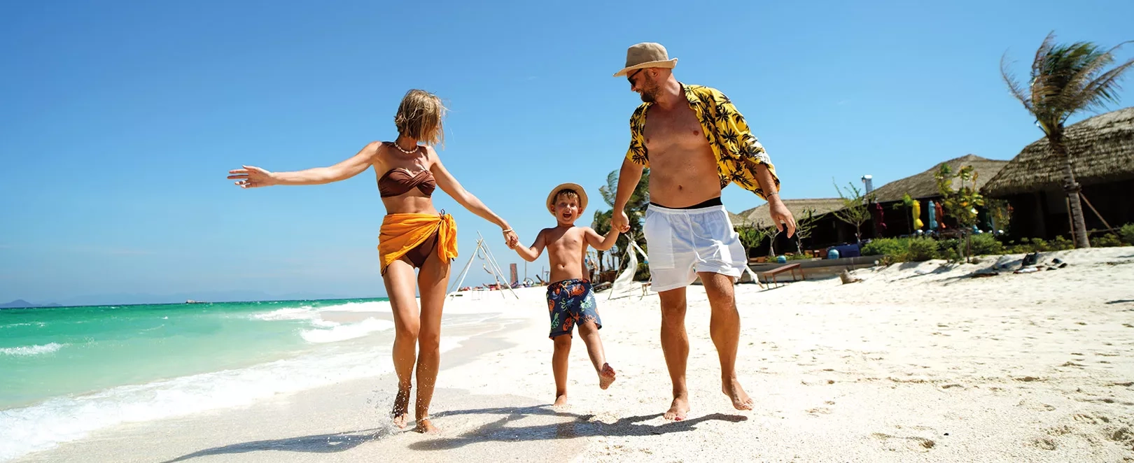 Couple avec un enfant courant sur le sable sur une plage de sable blanc
