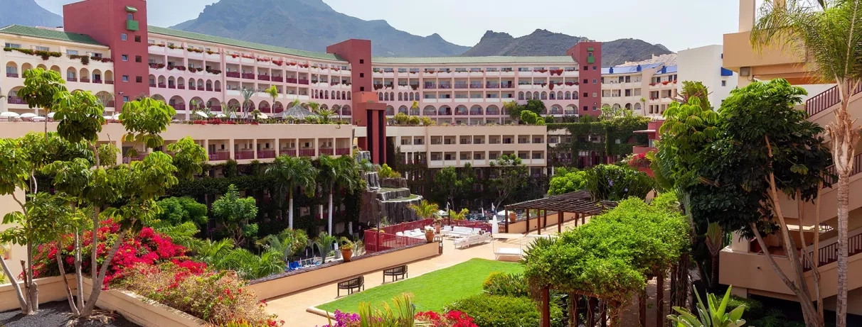 Une vue panoramique des jardins montrant des allées fleuries et l'architecture des bâtiments.