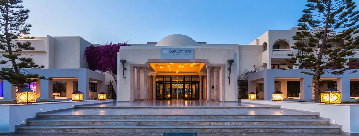 Façade illuminée de l'entrée principale du Djerba Aqua Resort pour un séjour de vacances en famille.