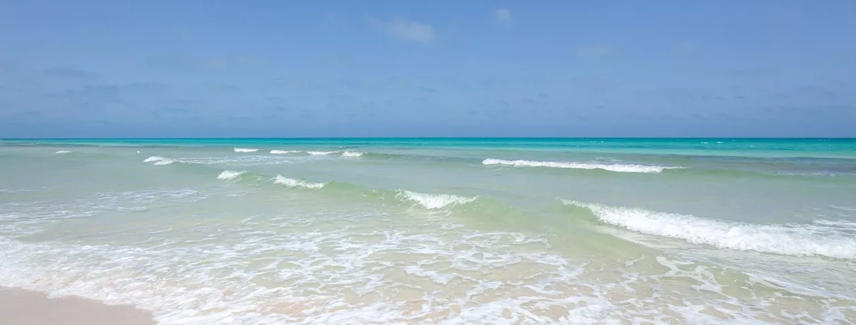 Plage de sable blanc et eaux turquoise de la mer Méditerranée au Djerba Aqua Resort, Tunisie.