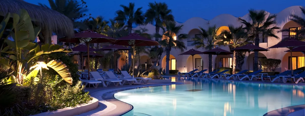 Piscine illuminée de nuit et architecture typique tunisienne pour un séjour détente au Djerba Beach.