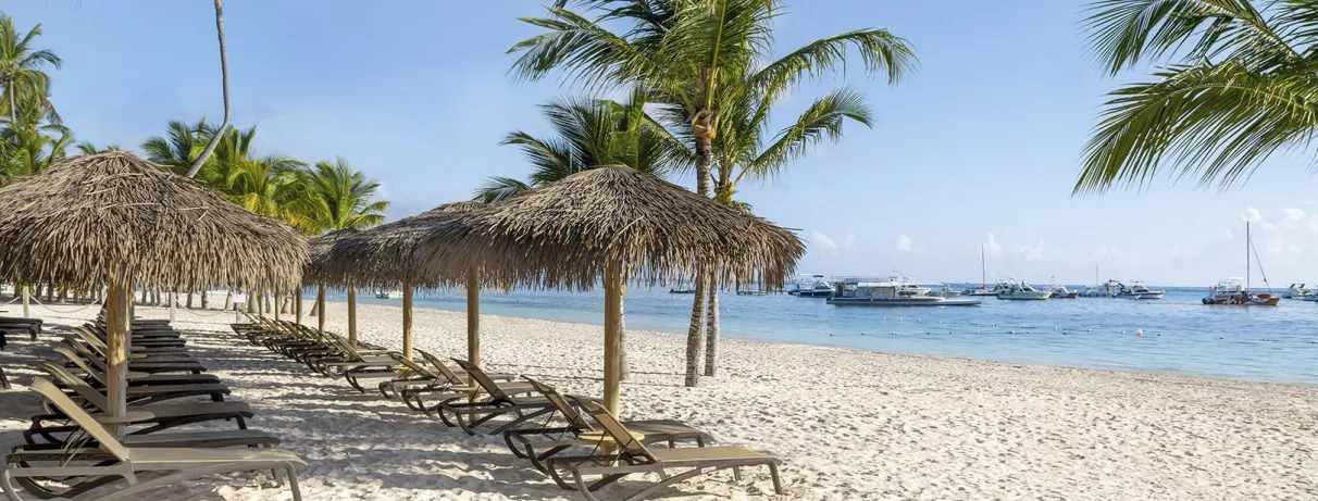 plage avec transats, sable blanc, bateaux, paillotes, palmiers