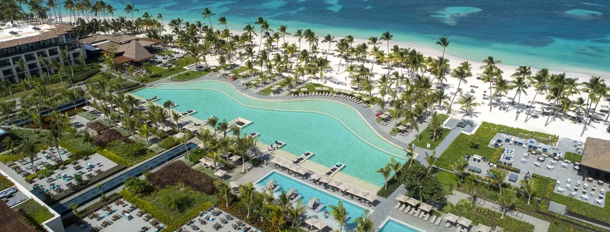 vue aérienne piscine et mer, eau turquoise, palmiers, hôtel, transat, sable blanc, végétation