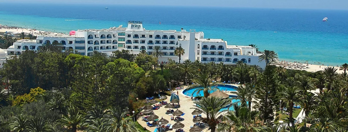 Vue aérienne de l'hôtel Marhaba Beach, jardins luxuriants, piscine et plage de sable blanc à Monastir en Tunisie.