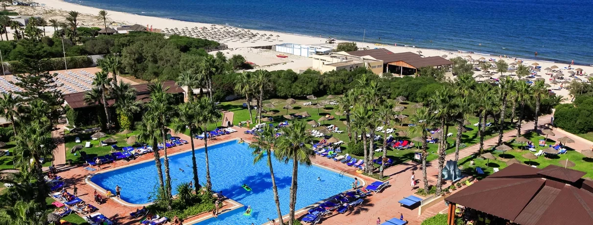 Vue aérienne complexe hôtelier Sahara Beach Monastir avec grande piscine, jardins et plage de sable fin.