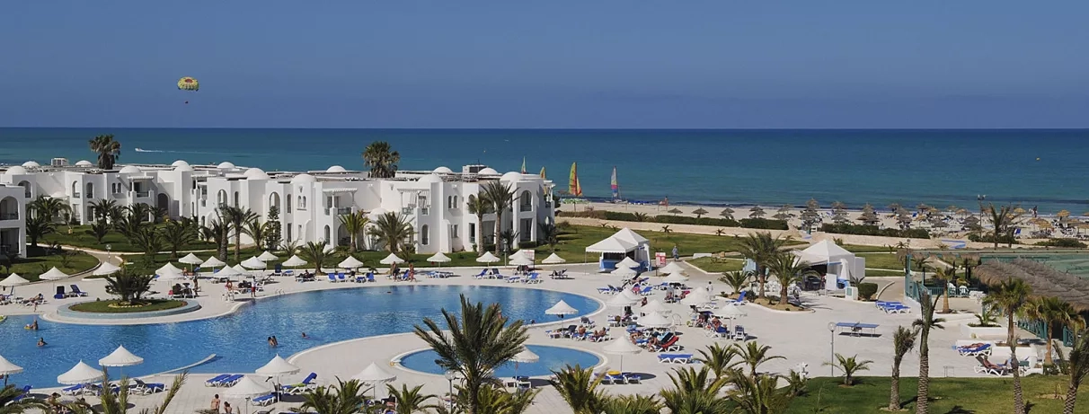 Jardin luxuriant et piscines du complexe hôtelier en bord de mer Méditerranée pour des vacances en Tunisie.