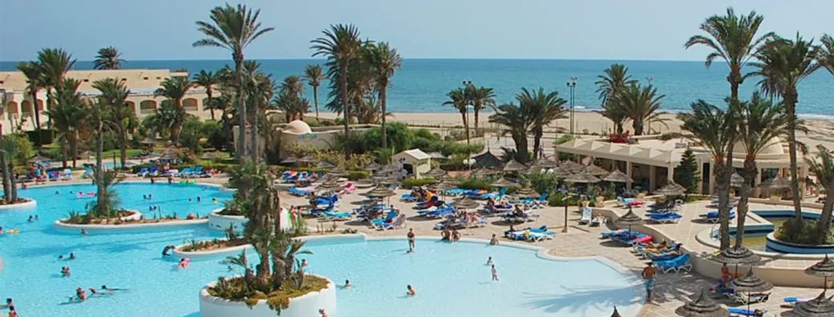 Grande piscine lagon et palmiers à l'hôtel Zephir Djerba en bord de mer Méditerranée, Tunisie.