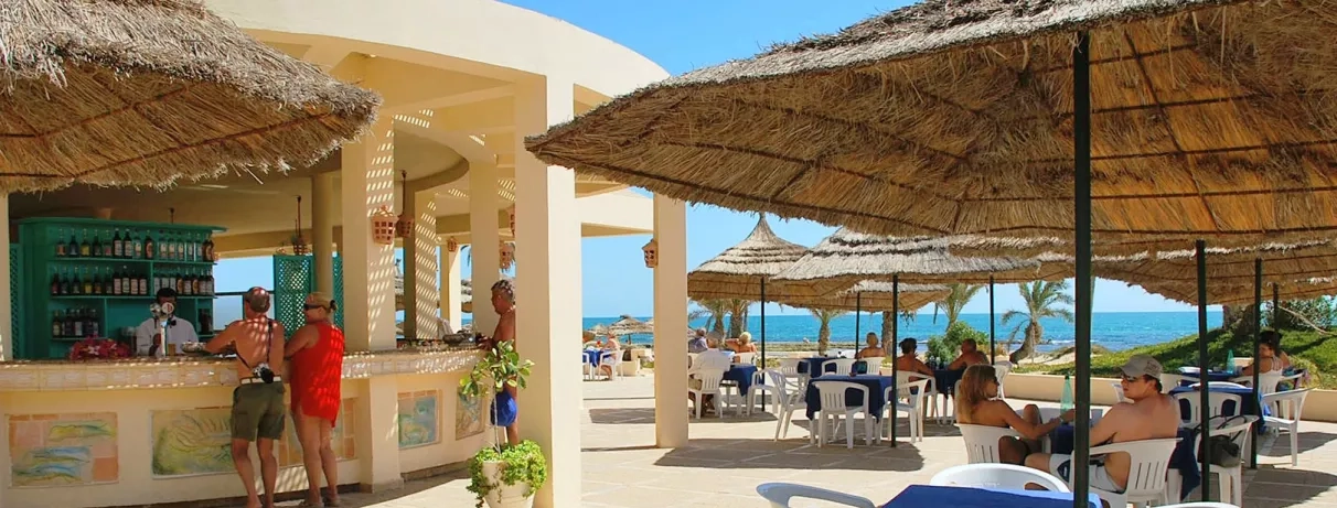 Bar de plage convivial avec parasols en paille et vue sur mer au Zephir à Djerba.