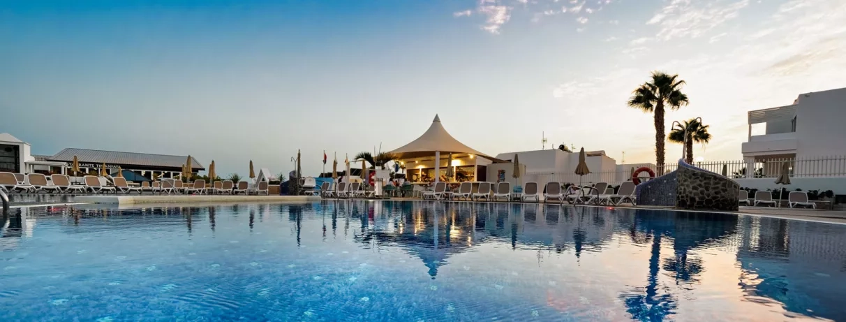 Un plan large et paisible montrant une structure centrale dans la piscine sous un ciel clair.