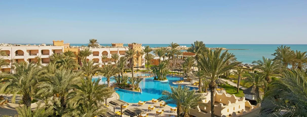 Vue panoramique sur les jardins, la piscine bleue et la plage méditerranéenne du complexe touristique Safira Palms Djerba.