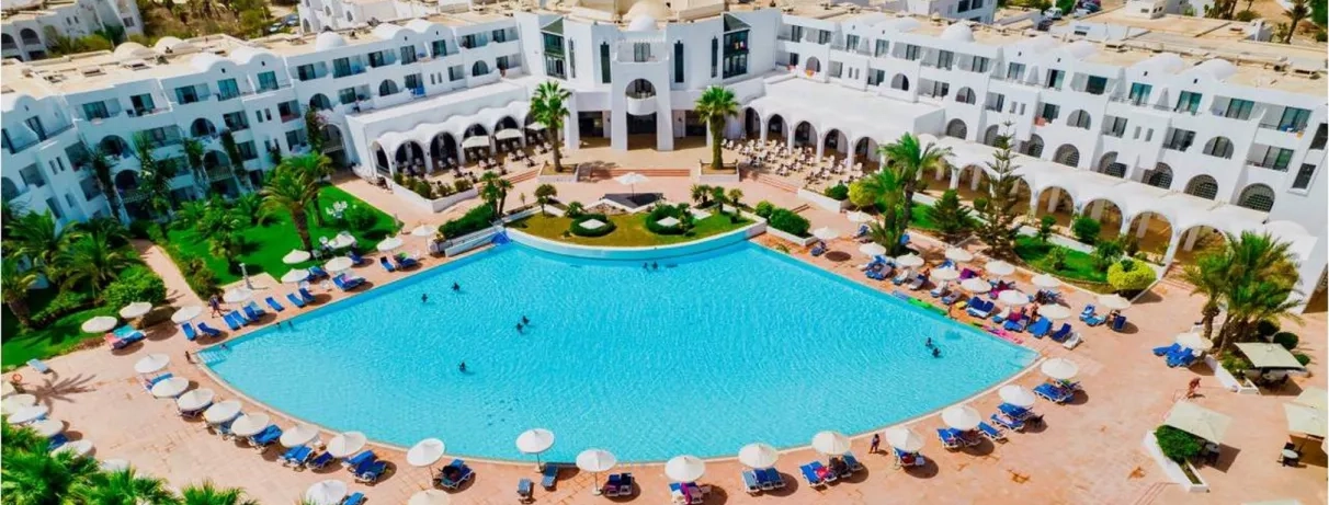 Grande piscine extérieure et architecture blanche typique de l'hôtel Palm Azur en Tunisie.