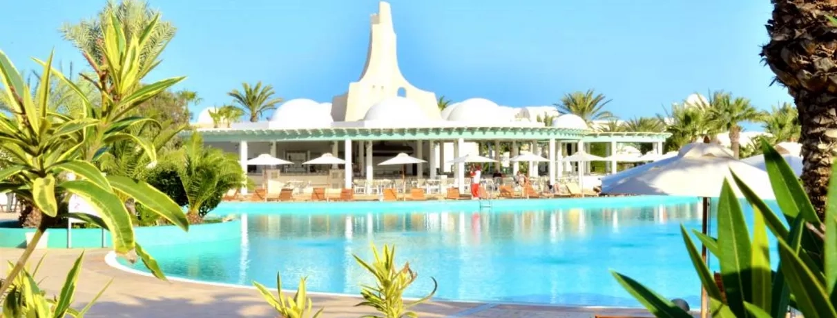 Architecture orientale blanche et piscine turquoise sous le soleil, complexe hôtelier de luxe à Djerba.