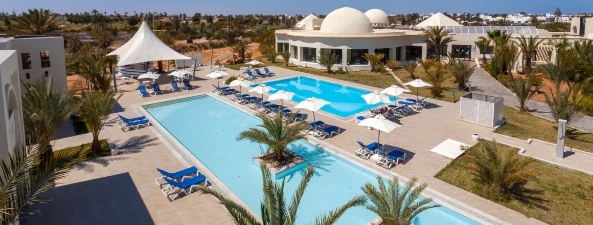 Bassins de baignade et terrasses avec parasols sous le ciel bleu de Djerba en Tunisie.