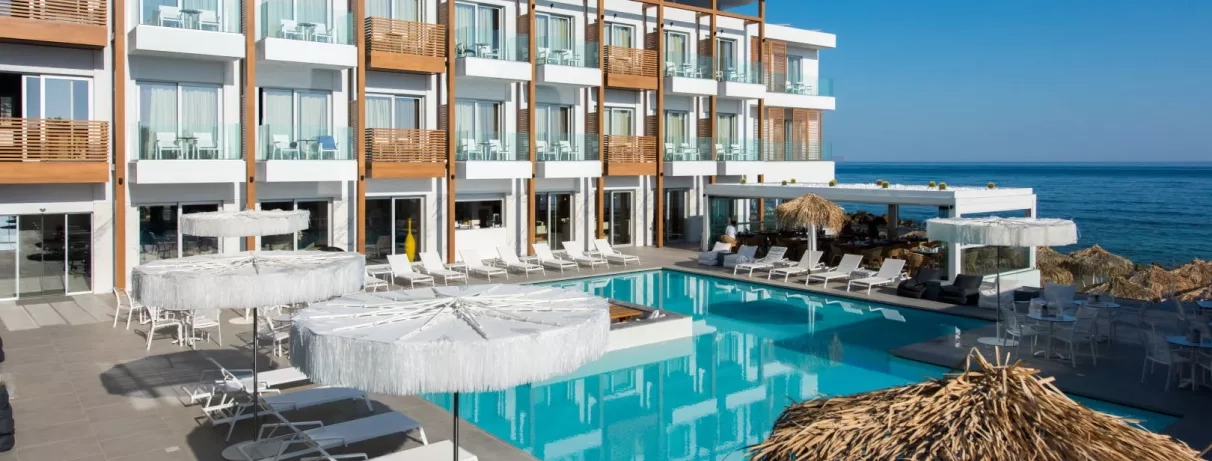 piscine avec transats, parasols, pieds dans l'eau, hôtel avec balcons couleur bois