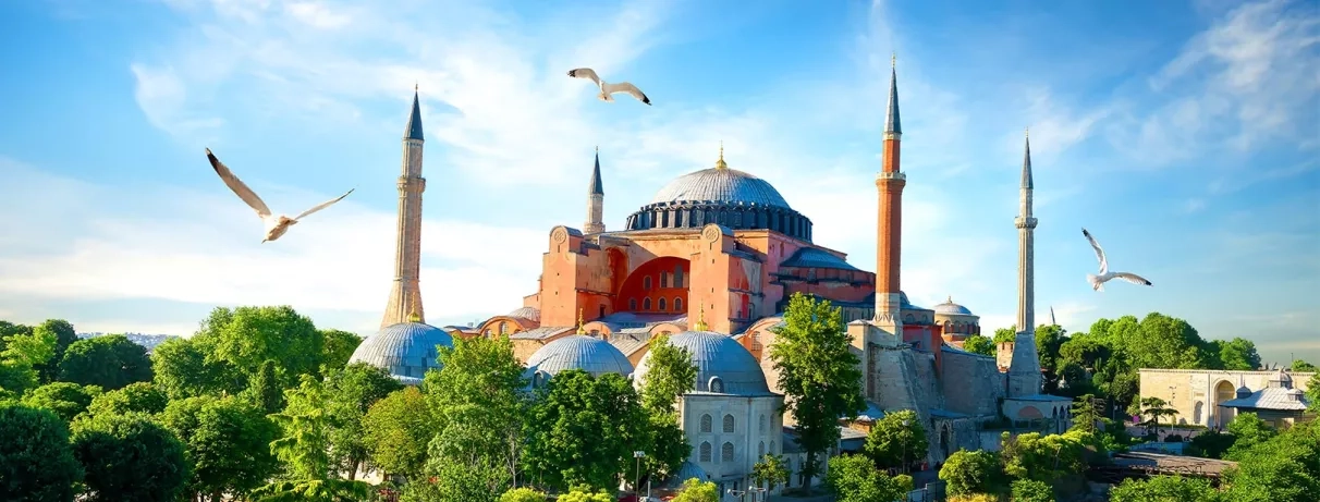 Vue de la mosquée emblématique, entourée de verdure, sous un ciel azur.