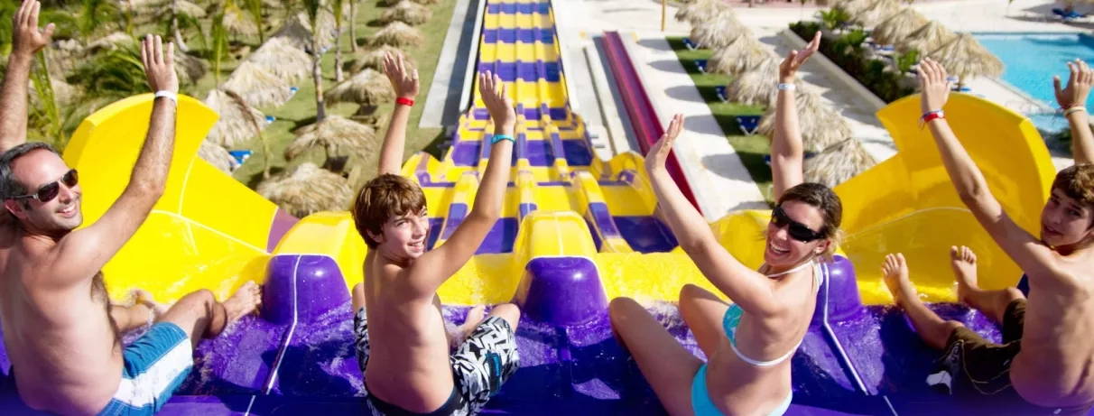 Toboggans jaune et violet, famille souriante deux adultes et deux jeunes garçons