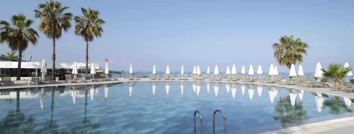 Un bassin aux eaux cristallines où se reflètent des palmiers sous un ciel bleu.