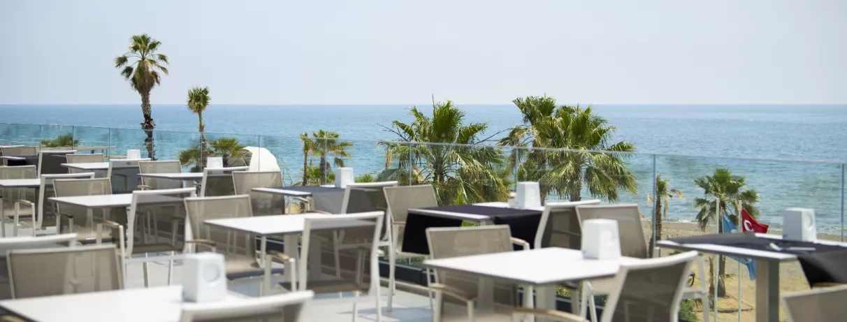 Des tables élégantes installées sur une terrasse ensoleillée avec une vue panoramique sur l'océan.