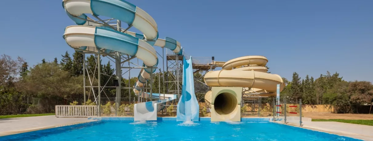 Trois grands toboggans aquatiques plongeant dans une piscine