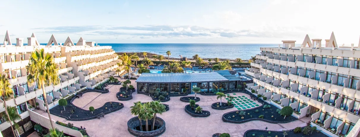 Une vue d'ensemble du complexe hôtelier, avec des bassins et des espaces de détente face à la mer.