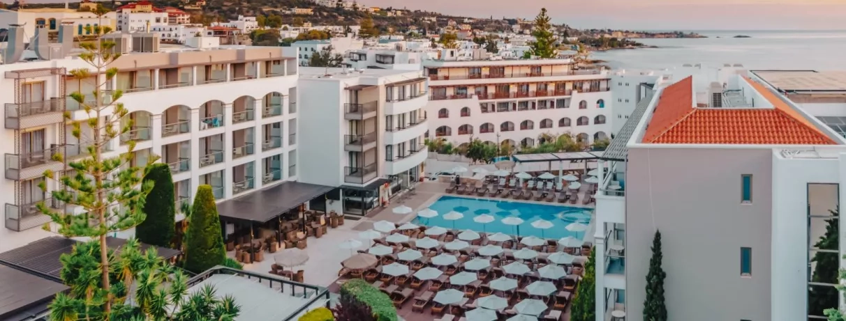 Vue panoramique du bâtiment de l'hôtel et de la piscine extérieur entourée de transats  