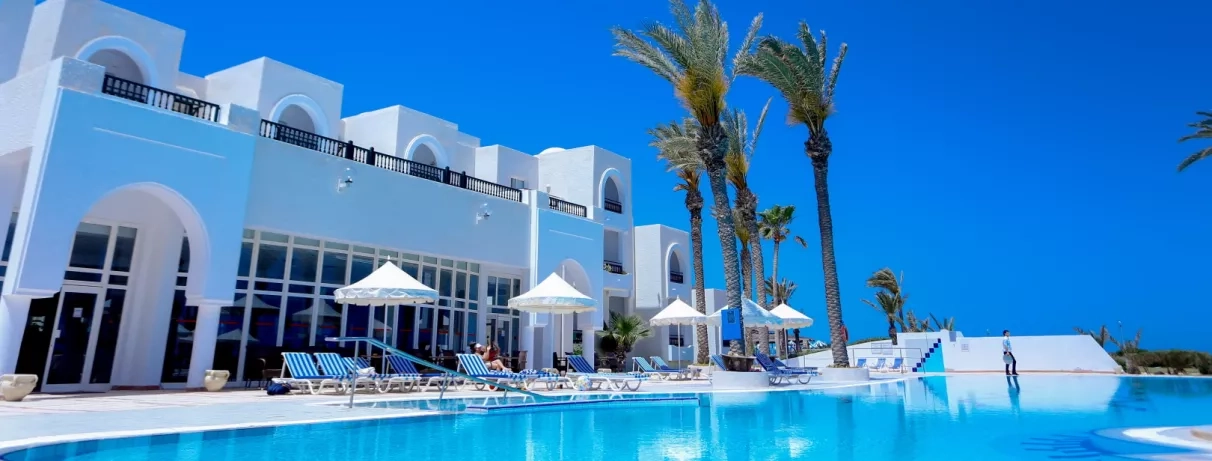 Transats et parasols au bord de la piscine bleue sous un soleil radieux à Al Jazira Beach.