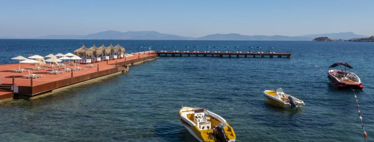 Une vue sur la mer avec quelques bateaux, avec un ponton aménagé s'avançant dans l'eau.