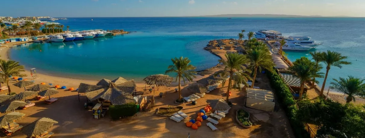 vue général avec transats au bord de la mer, palmiers, yachts sur le quai de la plage