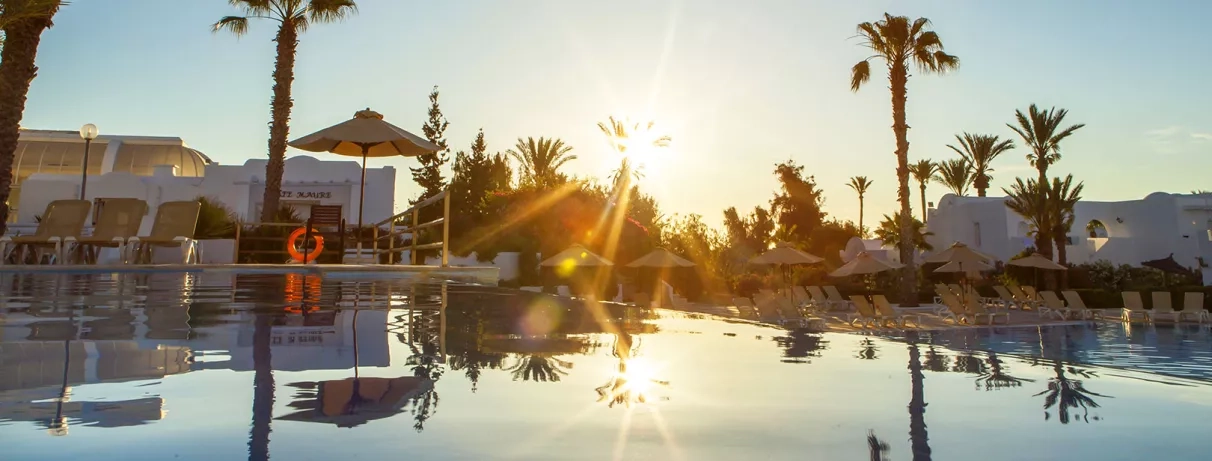 Coucher de soleil spectaculaire sur la piscine principale du complexe hôtelier Seabel Aladin en Tunisie.