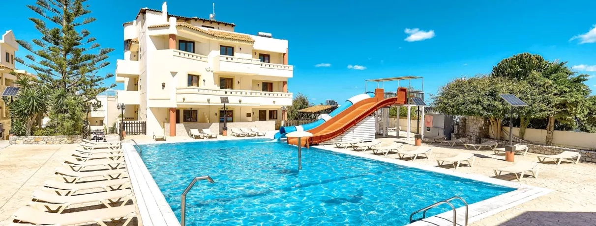 piscine avec transats, deux toboggans, un couvert bleu et blanc, l'autre découvert orange, oliviers, ciel bleu avec quelques nuages