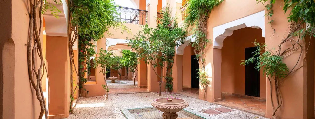 Patio dans le bâtiment des chambres avec une fontaine au milieu et des végétations au coin