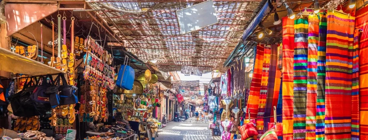 Une allée couverte du souk fourmille de marchandises colorées et de tissus suspendus.