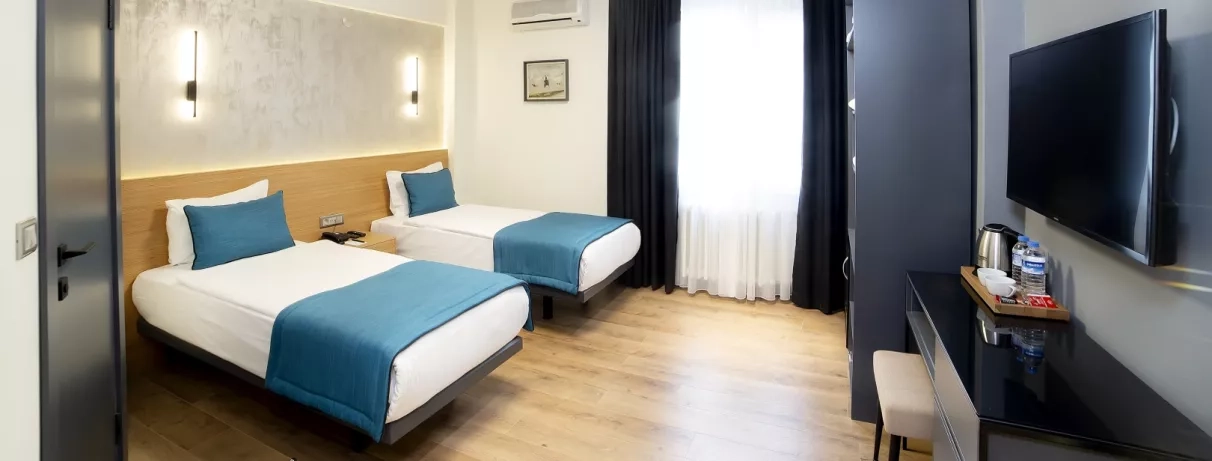 chambre avec deux lits simples et une télévision murale