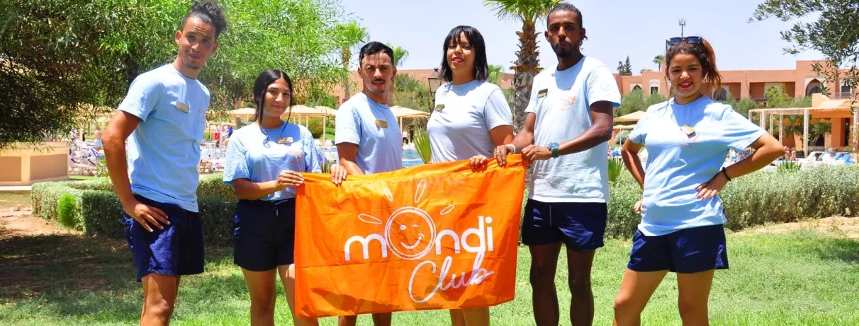 équipe d'animation avec une tenue uniforme et le drapeau de mondi club au jardin de l'hôtel