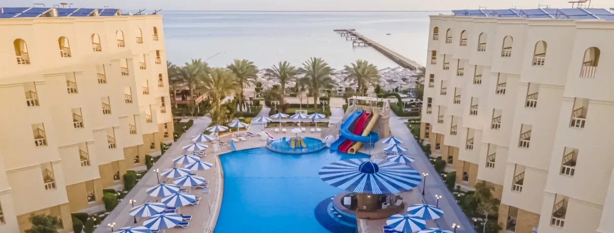 vue de haut de l'hôtel avec le bâtiment et la piscine au milieu, toboggans, transats, soleil, 