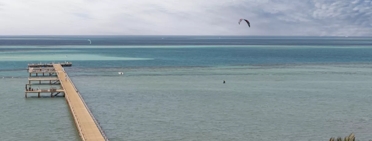 Vue de la plage avec ponton, horizon bleu, soleil