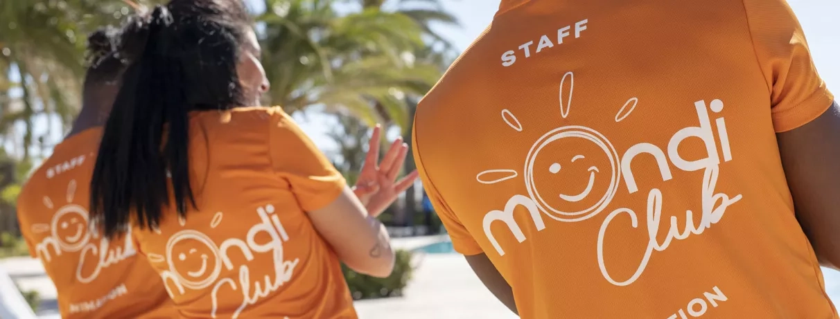 Le personnel souriant du Mondi Club portant des t-shirts orange vifs.