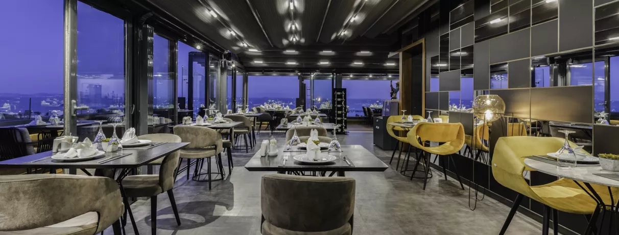 salle de restaurant avec des baies vitrées donnant sur la ville