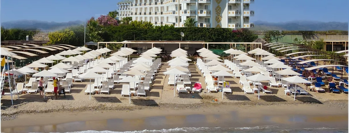 plage avec le mer et parasols et transats et en fond vue de l'hôtel
