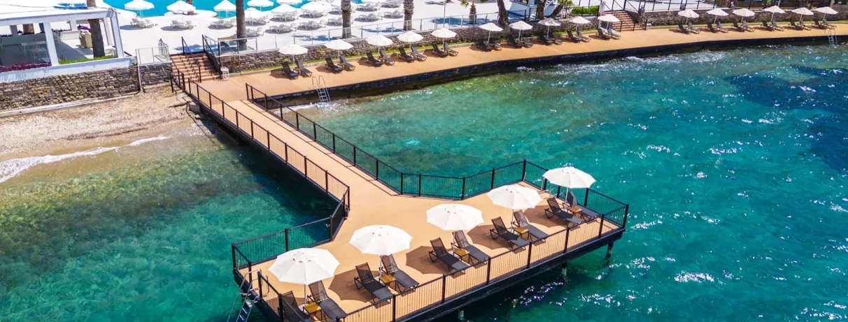 vue de la mer avec un ponton avec transats et parasols 