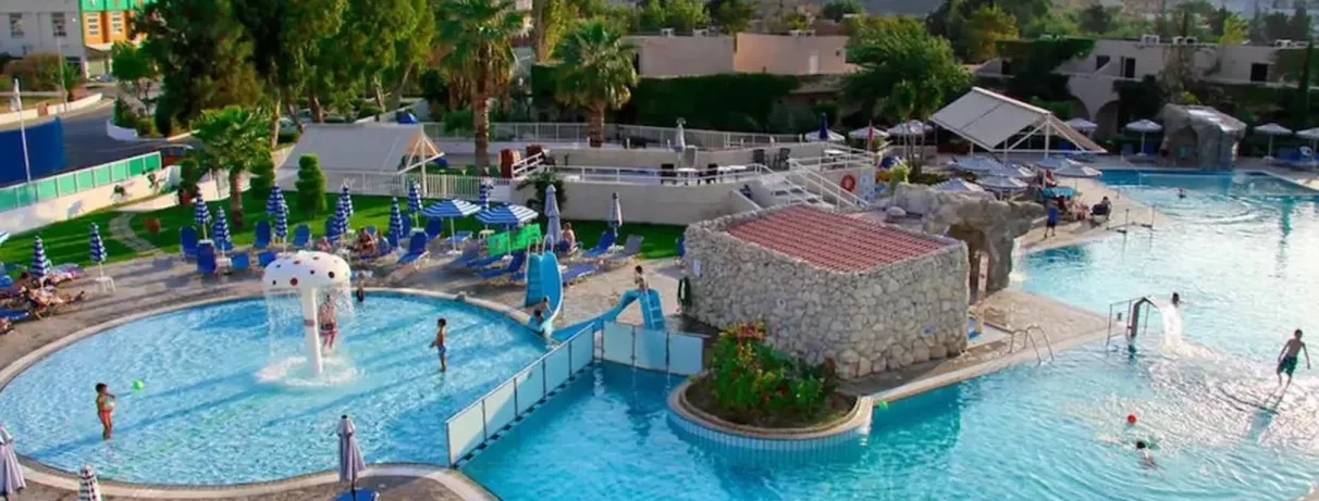 piscine avec fontaine en forme de champignon, parasols bleu, palmiers