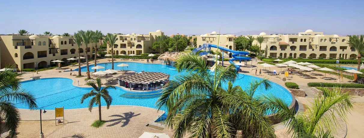Grande piscine lagon, toboggans aquatiques et palmiers au Mondi Club Stella Gardens Resort & Spa, Hurghada Égypte.