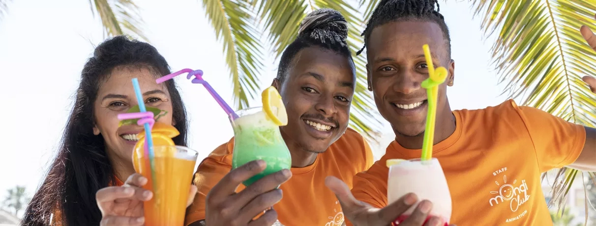 Équipe d'animation souriante proposant des cocktails tropicaux lors d'un séjour tout compris à Djerba.