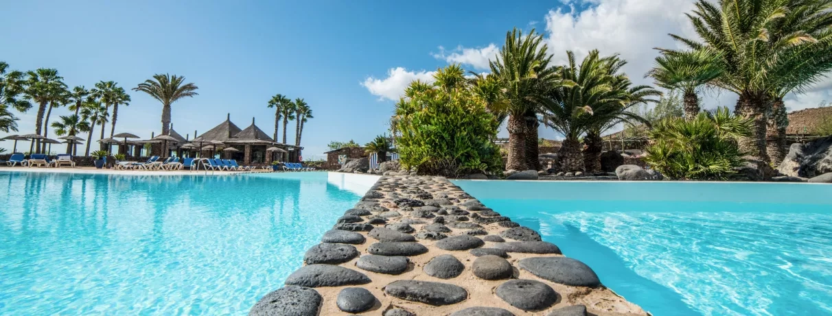 Un gros plan sur une séparation en pierre entre deux sections de la piscine, offrant une vue vers les jardins.