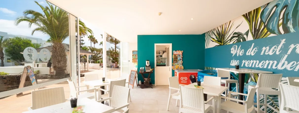 L'intérieur d'un bar ouvert et lumineux, décoré de murs bleu canard et de mobilier blanc.