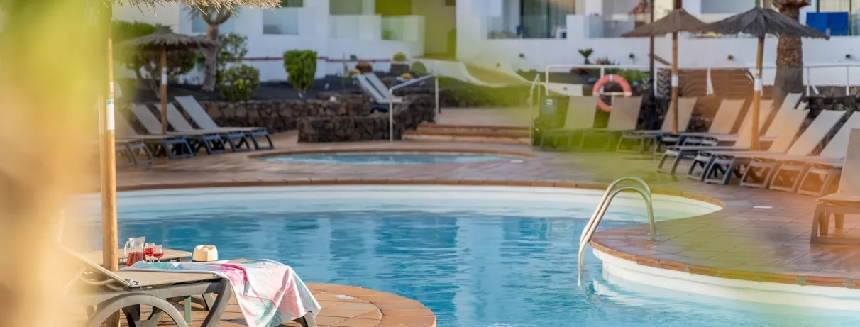 Un plan rapproché sur les rangées de chaises longues installées au bord de l'eau, sous le soleil.