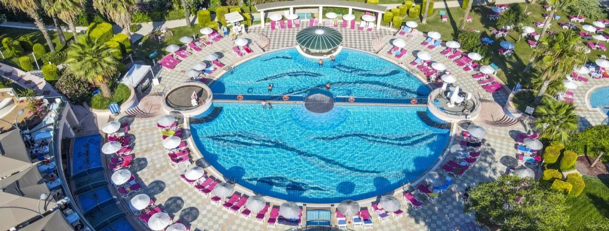 Une vue plongeante sur une grande piscine, entourée de nombreux transats roses.