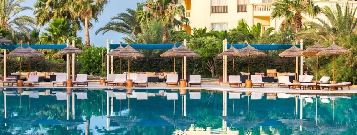 Piscine bordée de palmiers et transats ombragés, ambiance paisible et estivale